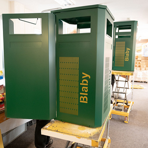 Two green Derby E Contemporary bins being backed with yellow backing plates for Blaby Distric Council.